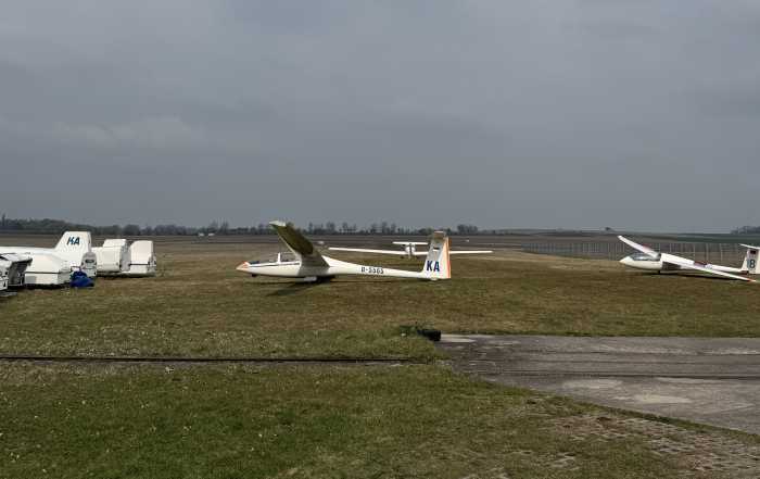 2 Segelflugzeuge stehen aufgerüstet vorm Hangar, links daneben sieht man die Anhänger wo diese drinnen waren